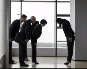 Asians in a business set up but bowing down to greet each other which is their form of etiquacy