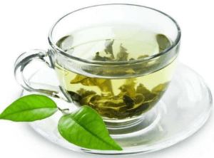 The picture shows a cup of green tea and its leaves 